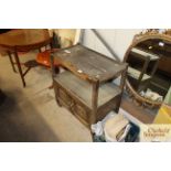 An oak two tier tea trolley with cupboard base