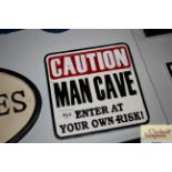 A novelty sign "Caution Man Cave"