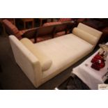 A cream upholstered chaise longue with scroll loos