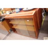 A teak display cabinet enclosed by glass sliding d