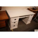 A white pedestal desk, having central pull out key