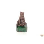 A bronze figure of a seated bear on faux malachite