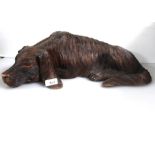 A carved wooden ornament of a recumbent dog