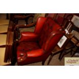 An ox blood leather wing back armchair