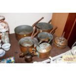 A collection of antique copper saucepans, kettle a