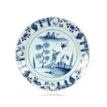 A mid 18th Century Bristol Delftware charger, painted in blue with an Oriental figure and diving