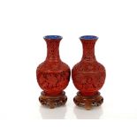 A pair of Chinese cinnabar lacquered vases, on wooden stands of baluster form with blue enamel