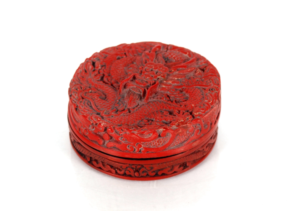 A Chinese cinnabar lacquered circular box and cover, decorated in relief with a dragon and similar