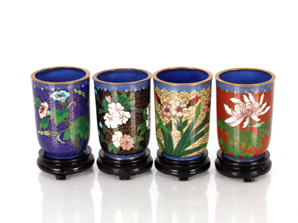 A set of twelve 20th Century cloisonné cups on wooden stands, decorated with a variety of flowers