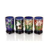 A set of twelve 20th Century cloisonné cups on wooden stands, decorated with a variety of flowers