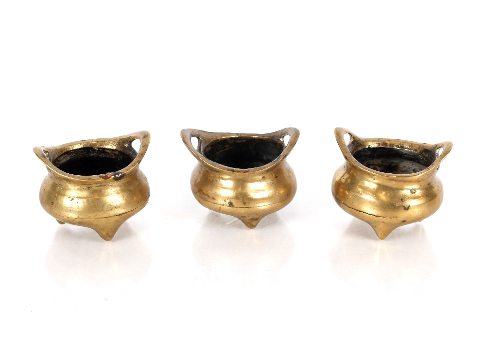 A pair of 19th Century Chinese bronze miniature censers, each flanked by upswept strap handles on