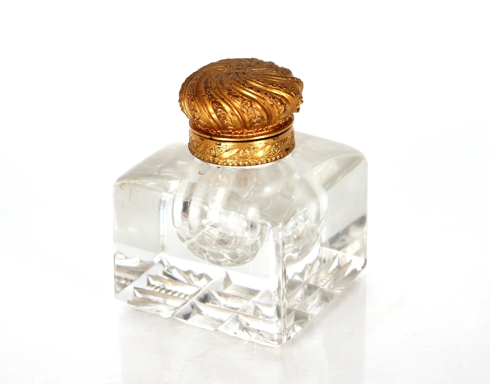 A heavy 19th Century glass inkwell, with gilt metal lid