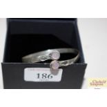 A boxed white metal and rose quartz bangle