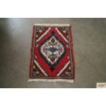 An approx. 2'2" x 1'6" red patterned rug