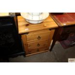 A stripped pine three drawer bedside chest