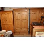 A stripped pine wardrobe fitted drawer to base