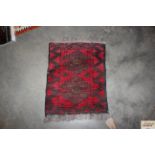 An approx. 2' x 1'7" red and black patterned rug