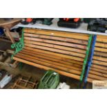 A wooden slatted garden bench with green painted c