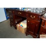 A reproduction mahogany desk with a green leather