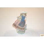 A Lladro figurine of a girl carrying a basket of f