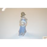 A Lladro porcelain figure of a girl carrying a flo