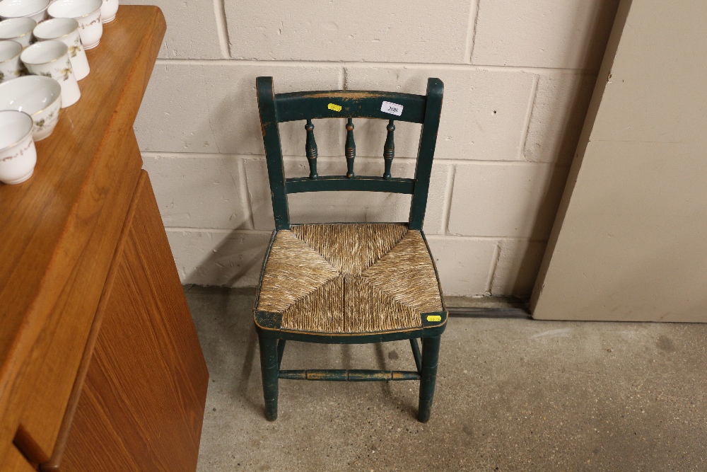 A green painted child's chair with rush seat