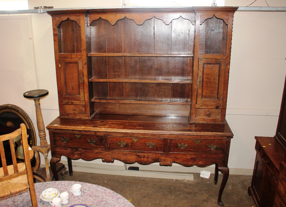 An antique oak dresser, the shelved boarded back with cupboards and drawers, three drawers to the