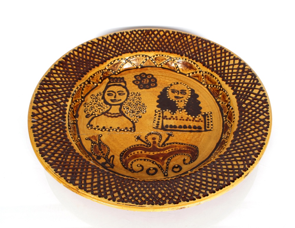 A large circular Staffordshire slipware dish, decorated with King and Queen, circa 1850 AF, 61cm