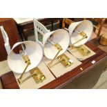 Three brass folding wall lights and shades