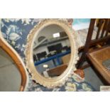 An oval wall mirror contained in gilt frame