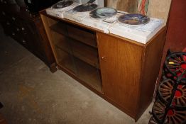 A teak low bookcase enclosed by glazed sliding doo