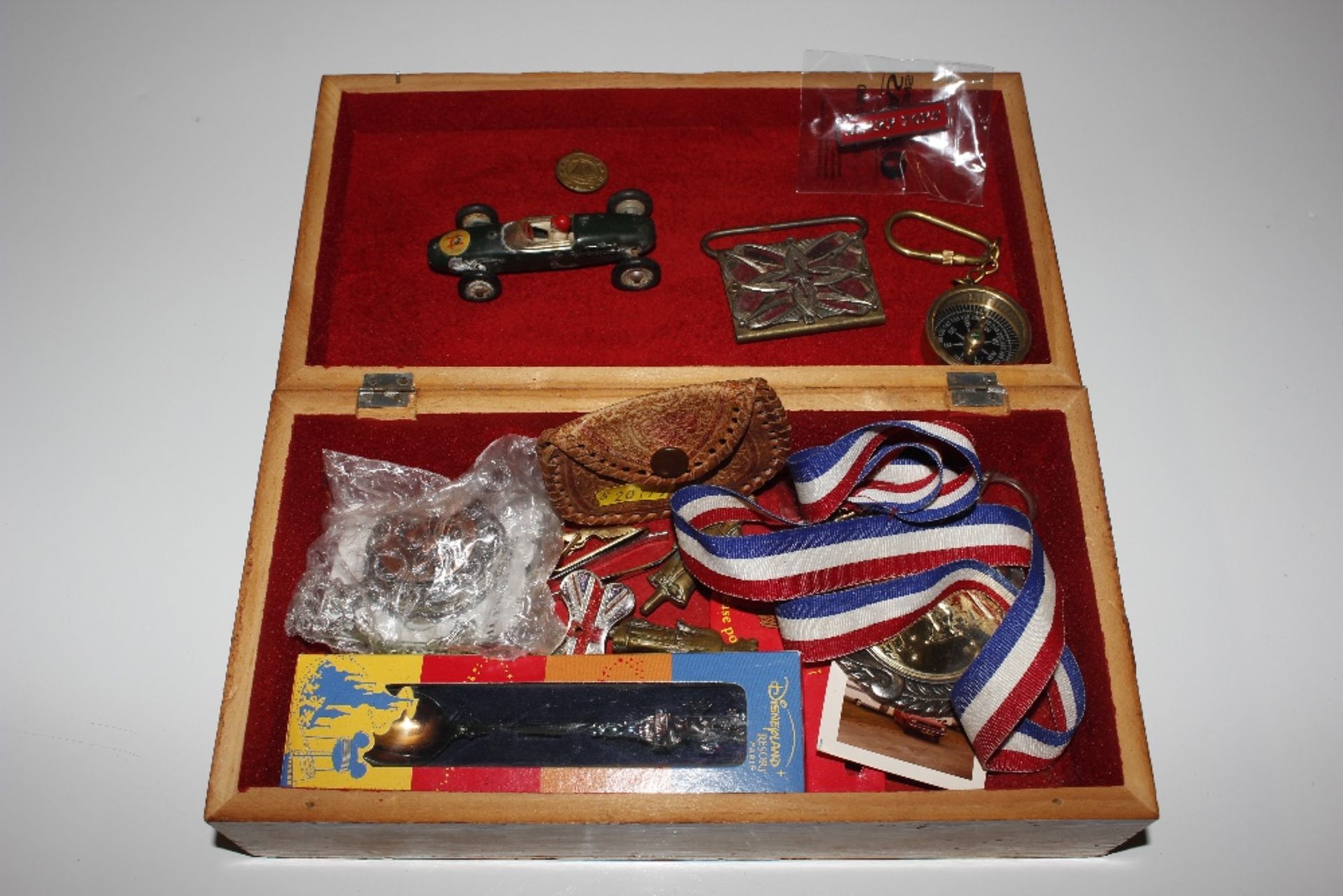 A wooden box containing a toy car, various medalli