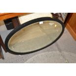 An oval and bevel edged wall mirror