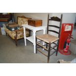 An oak ladder back rush seated chair and a white painted two tier table raised on turned supports