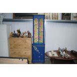 A painted and decorated upright corner cabinet