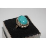 A white metal dress ring set with turquoise stone