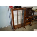 A walnut veneer display cabinet raised on squat ca