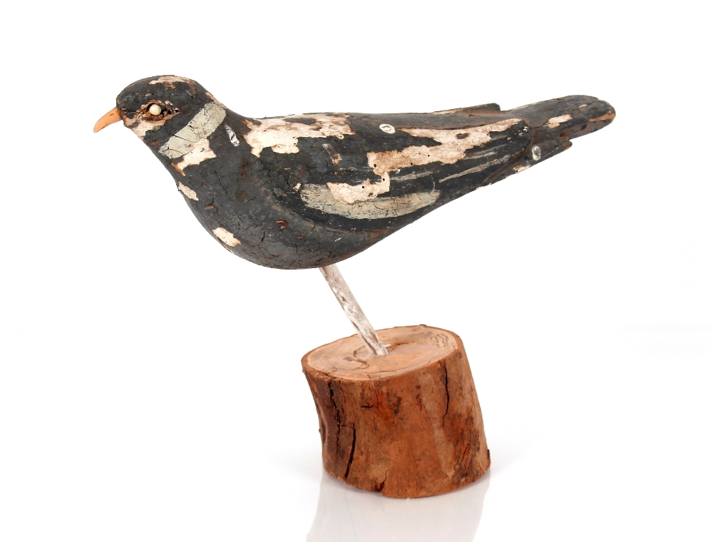 A 19th Century painted wooden decoy pigeon raised on a later base, 39cm long, 30cm high overall