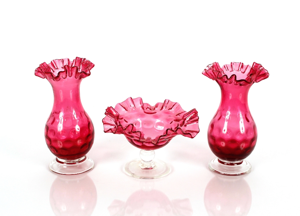 A pair of cranberry glass baluster vases having dimpled decoration and crimped rims raised on