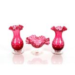 A pair of cranberry glass baluster vases having dimpled decoration and crimped rims raised on