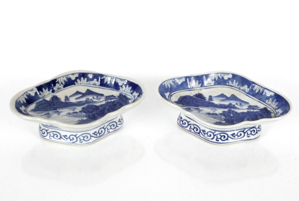 A pair of 19th Century Chinese pedestal dishes of oval shape decorated river scenes with mountains