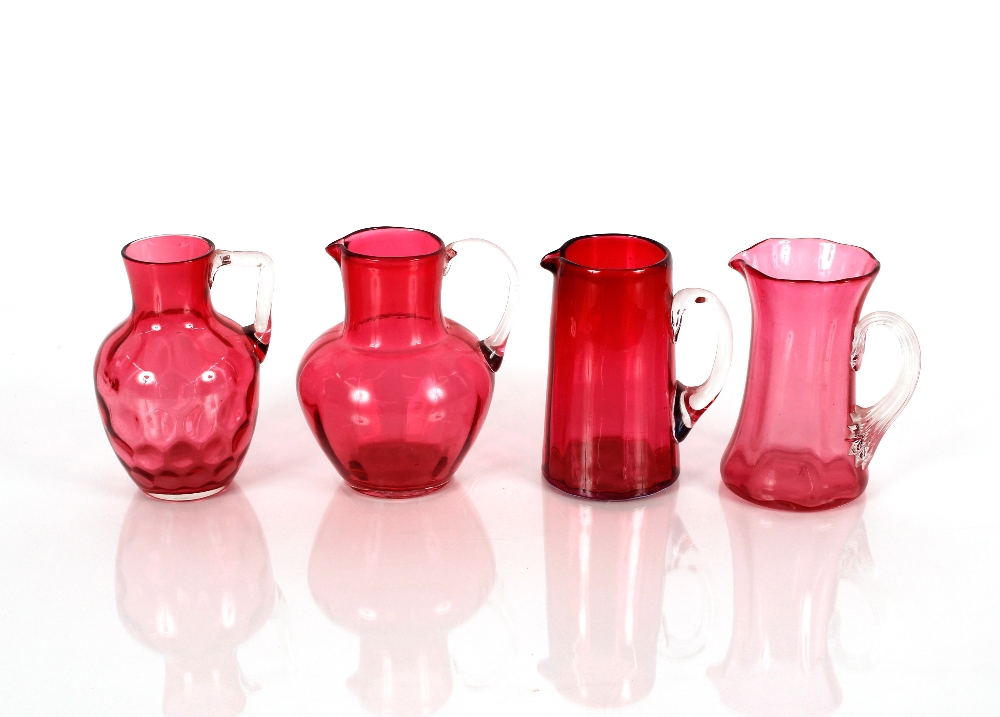 Four various cranberry glass jugs with clear glass handles