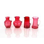 Four various cranberry glass jugs with clear glass handles