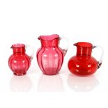 Three cranberry glass baluster water jugs with clear glass handles