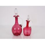 A cranberry glass baluster claret jug with clear glass globular stopper, 34cm high; and a smaller