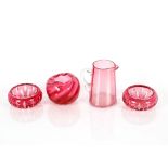 A pair of cut glass cranberry tinted salts; a cranberry cream jug with clear glass handle; and a