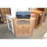 A stripped pine corner cabinet