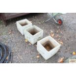 Three concrete garden planters decorated with hors