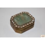 A brass box with hardstone inset surrounded by whi