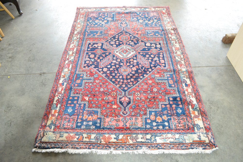An approx. 7'1" x 4'3" Persian red and blue patter